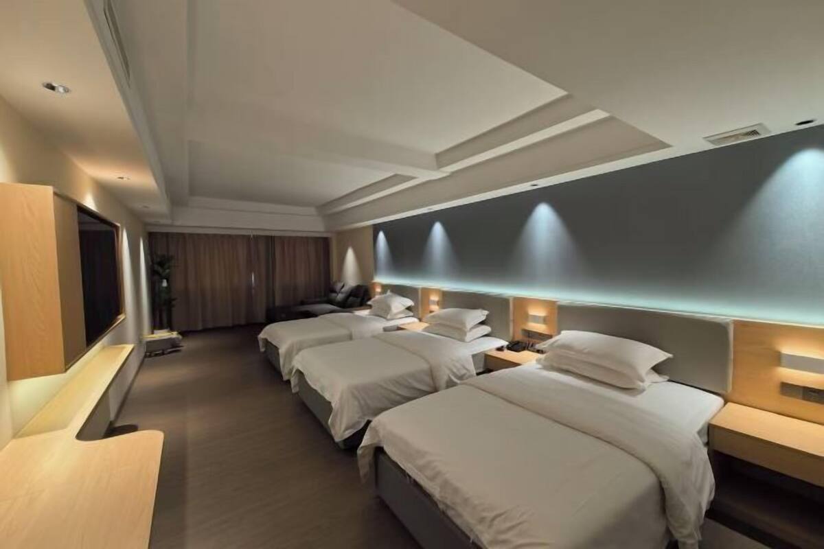 A hotel room with a modern design, featuring a large bed, a desk, and a television.