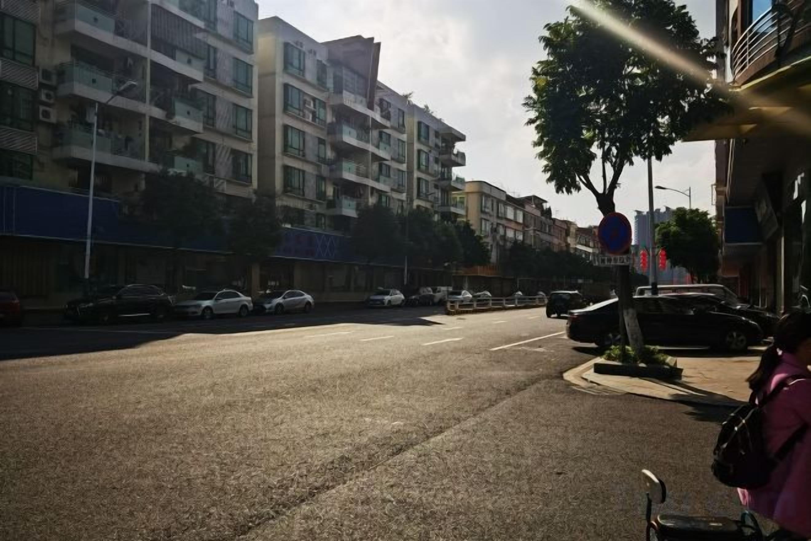 A street with parked cars and a building with multiple floors.
