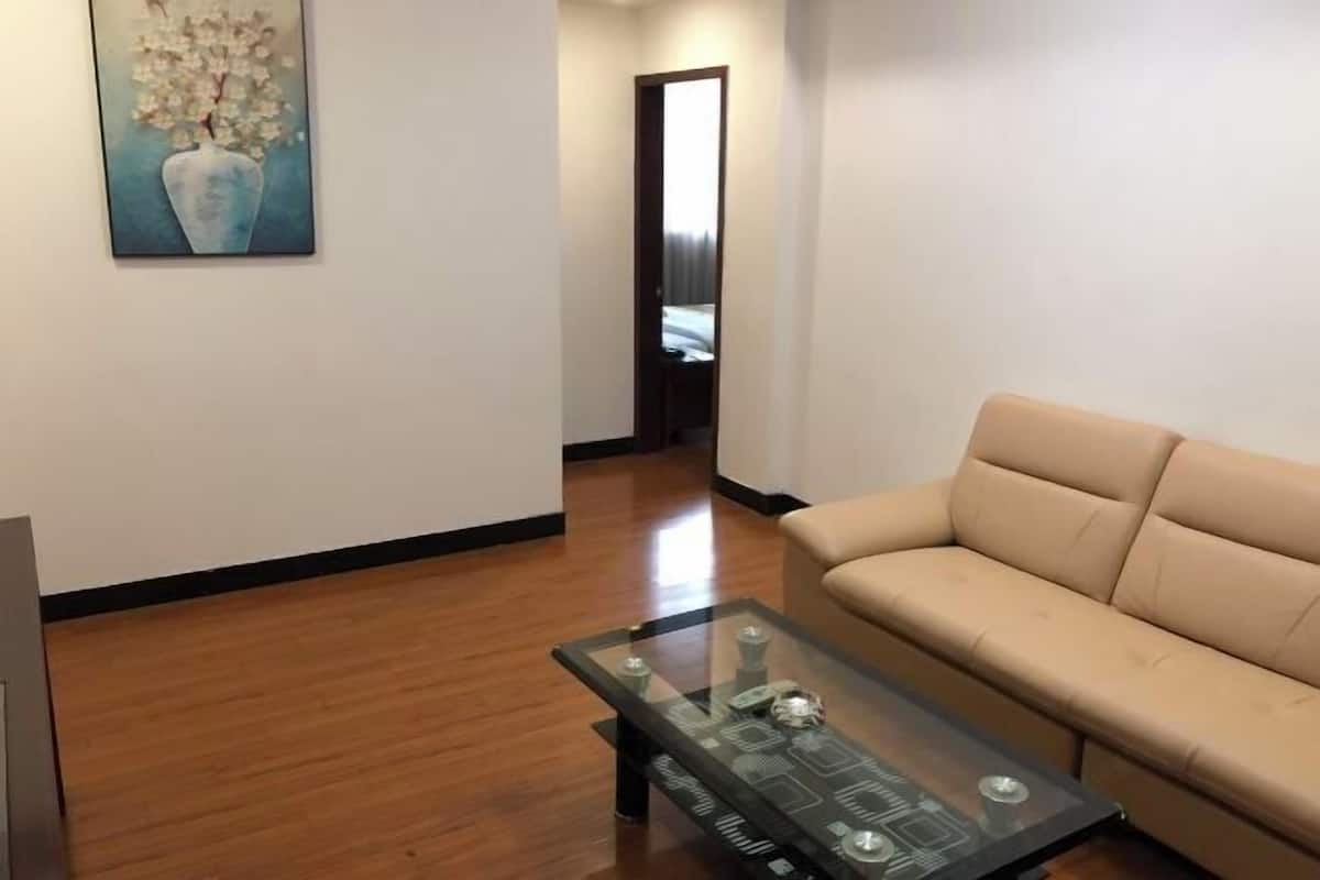 A living room with a glass coffee table, a beige sofa, and a painting on the wall.