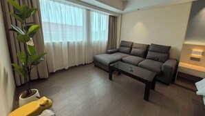 A modern living room with a sectional sofa, a coffee table, a potted plant, and a lamp. - Shunde Yufeng Hotel (Foshan)