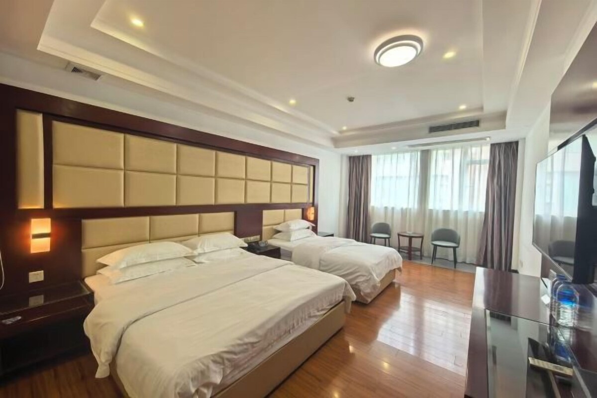 A hotel room with two beds, a flat-screen TV, and a seating area with a table and chairs.