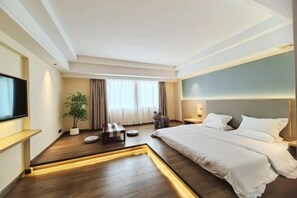 A modern hotel room with a large bed, a flat-screen TV, a potted plant, and a small seating area. - Shunde Yufeng Hotel (Foshan)