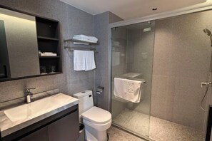 A modern bathroom with a glass shower enclosure, a white sink, and a toilet. - Shunde Yufeng Hotel (Foshan)