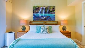 Une chambre à coucher comprenant un lit, deux tables de chevet, une lampe fixée au mur et un tableau représentant une cascade.