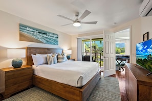 A bedroom with a bed, bedside tables, a ceiling fan, a painting, a TV, and a balcony with a view. - Mountain & Waterfall Views - Pool & BBQ (Princeville)