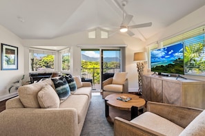 A living room with a sofa, chairs, a coffee table, a TV, and a balcony with a view. - Mountain & Waterfall Views - Pool & BBQ (Princeville)