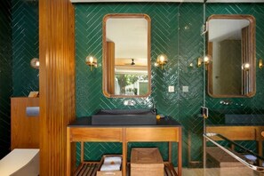 Bathroom features a herringbone-patterned tile backsplash, a vanity with a sink and mirror, and wall sconces.