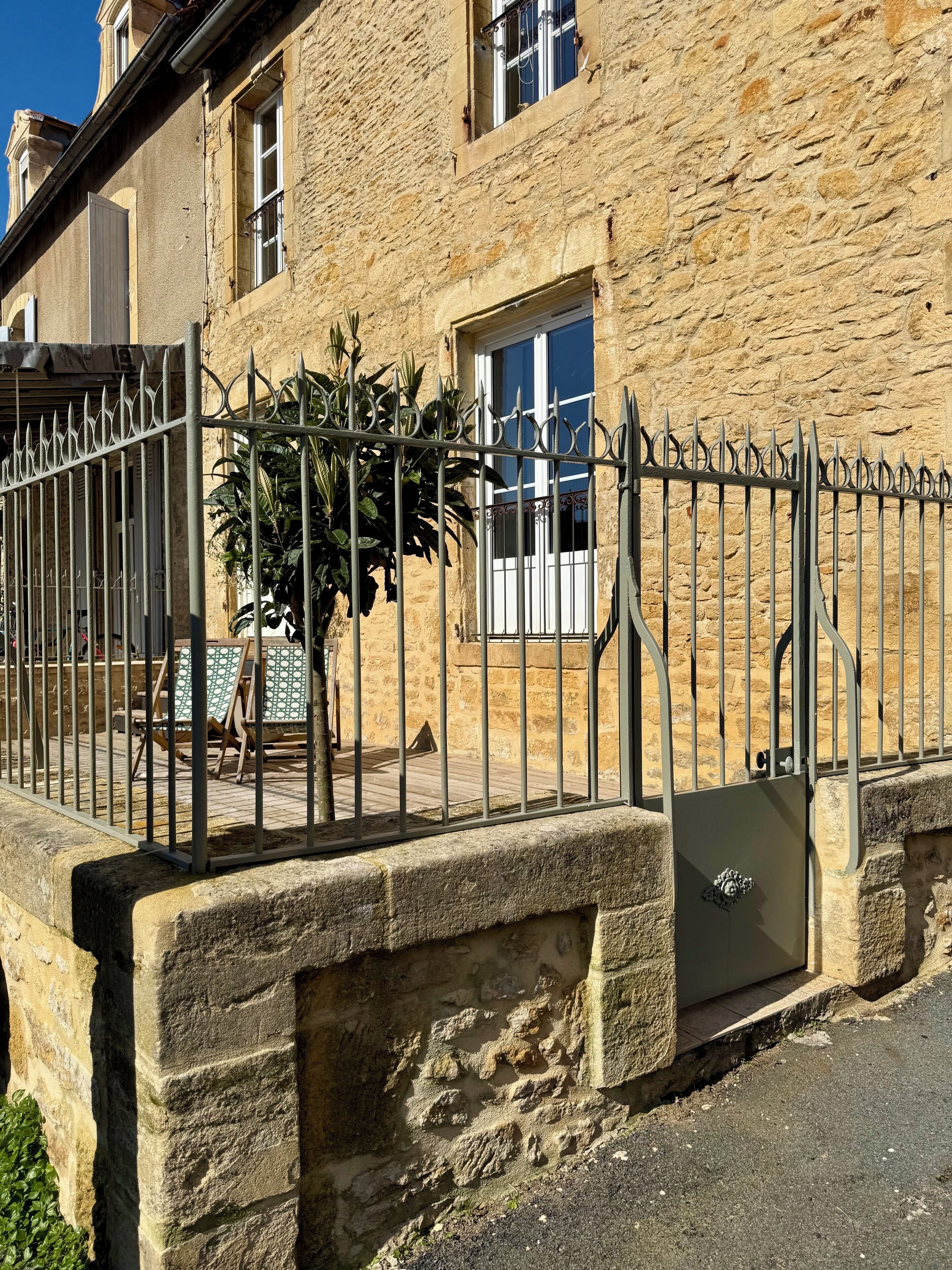 A stone building with a metal gate, a window, and a door.