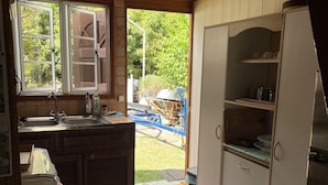 Cozinha com armários de madeira, pia e janela com vista para um jardim.