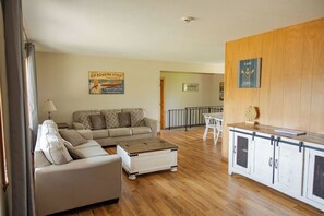 A living room with a sofa, coffee table, and a kitchen area with cabinets and a countertop.