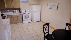 A kitchen with wooden cabinets, a white stove, a refrigerator, and a dining table with chairs. - Lake Cabin on North Long Lake (Brainerd)