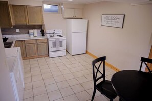 A kitchen with wooden cabinets, a white stove, a refrigerator, and a dining table with chairs.