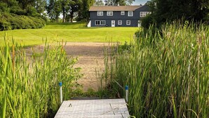 A pathway leading to a house with a grassy lawn and a metal dock. - Lake Cabin on North Long Lake (Brainerd)