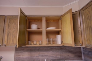A kitchen with wooden cabinets, open shelves, and a countertop.