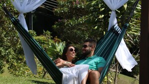 A hammock with white canopy, set in a grassy outdoor area with greenery in the background. - Pousada Realeza (Atibaia)