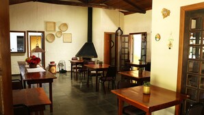 A cozy dining area with wooden tables and chairs, a large black stove, and various wall decorations. - Pousada Realeza (Atibaia)