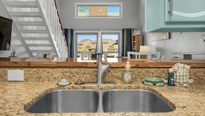 A kitchen with a stainless steel sink, granite countertop, and a view of the outside through a window. - 🌊 Gulf Views~Prime Spot~Pet Friendly~Steps to Beach~Vacay with a View 🌊 (Miramar Beach)