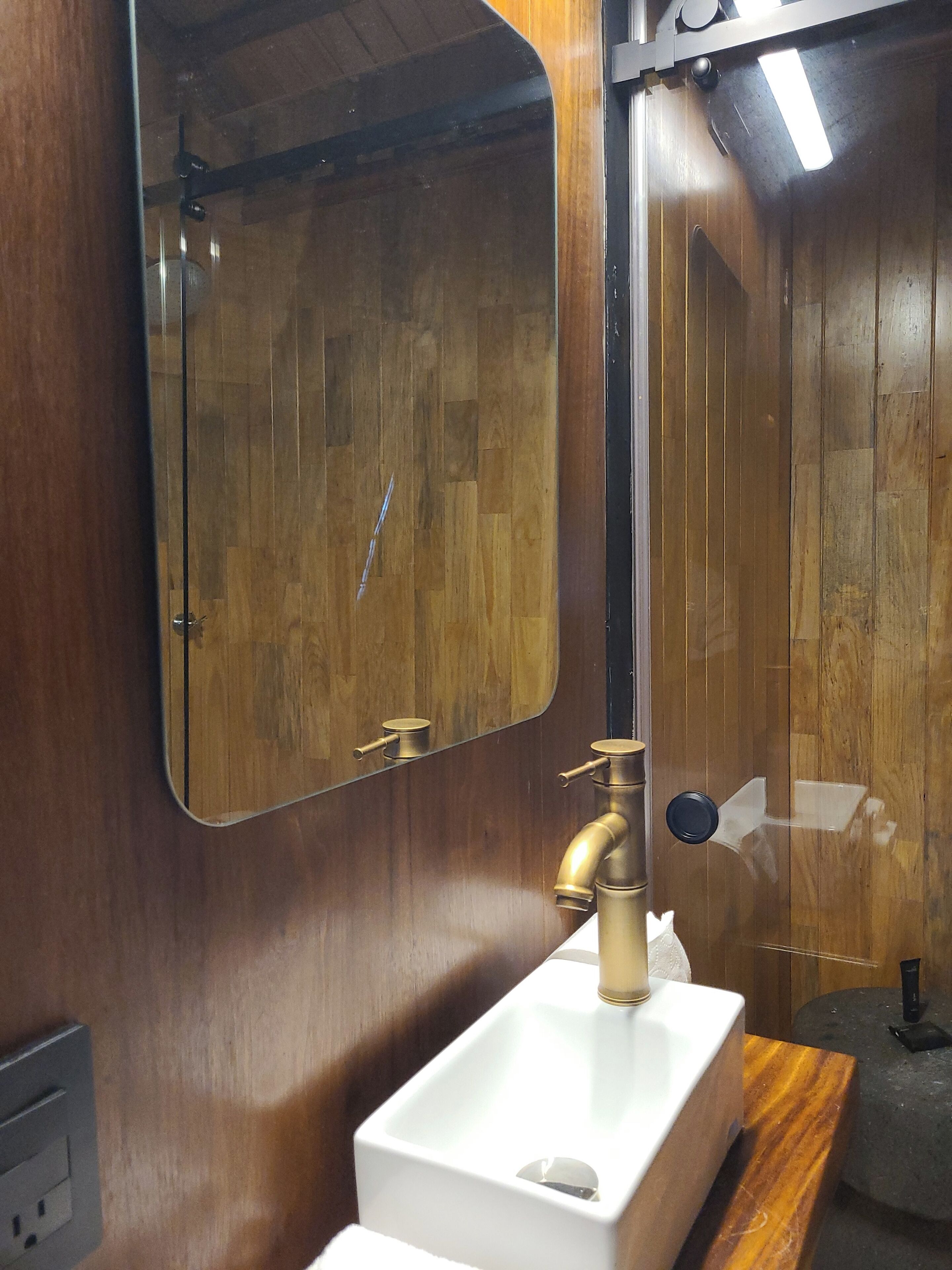 A bathroom with a wooden vanity, a white sink, and a mirror.