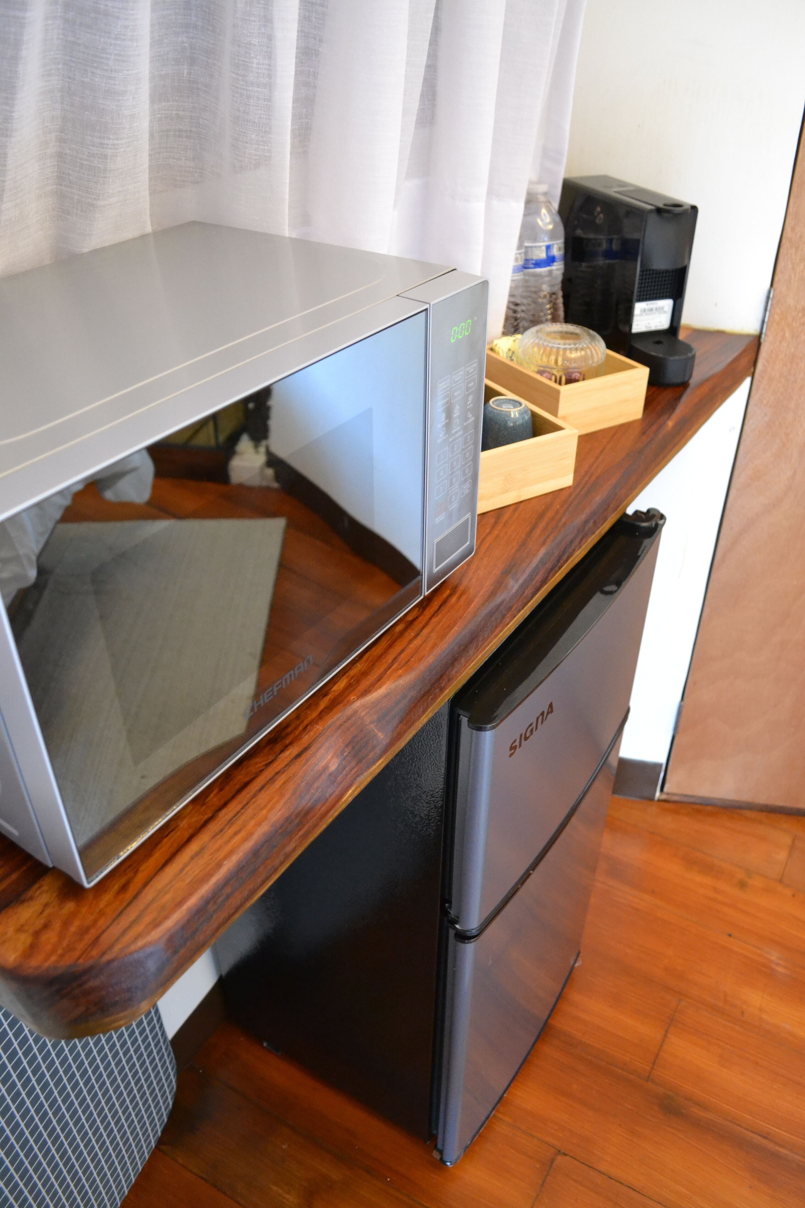 Una cocina compacta con microondas, cafetera y refrigerador.