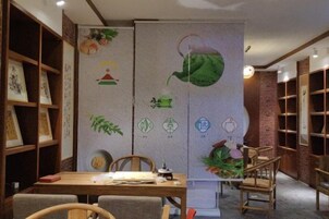 Una habitación con una mesa de madera, sillas, una estantería y un muro decorativo con varios símbolos y obras de arte.