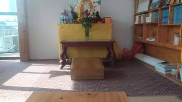 A room with a wooden table, a yellow altar, and a bookshelf.