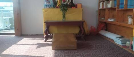 Una habitación con una mesa de madera, un altar amarillo y una estantería.