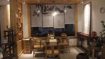 A dining area with wooden furniture, a large window with artwork, and a traditional Asian design.
