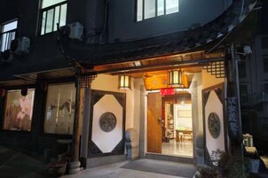 Un edificio tradicional con entrada de madera, ventanas amplias y un letrero con caracteres chinos.