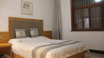 A bedroom with a wooden headboard, a bed with white bedding, a nightstand, a window with blinds, and a framed picture on the wall.