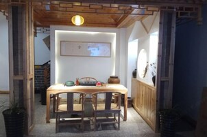 Un comedor con una mesa y sillas de madera, un mapa en la pared y un techo de madera con vigas a la vista.