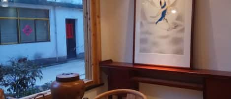 A traditional room with a wooden table, a ceramic pot, and a framed artwork on the wall.