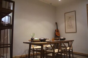 A dining area with a table, chairs, a guitar, and a framed artwork on the wall.