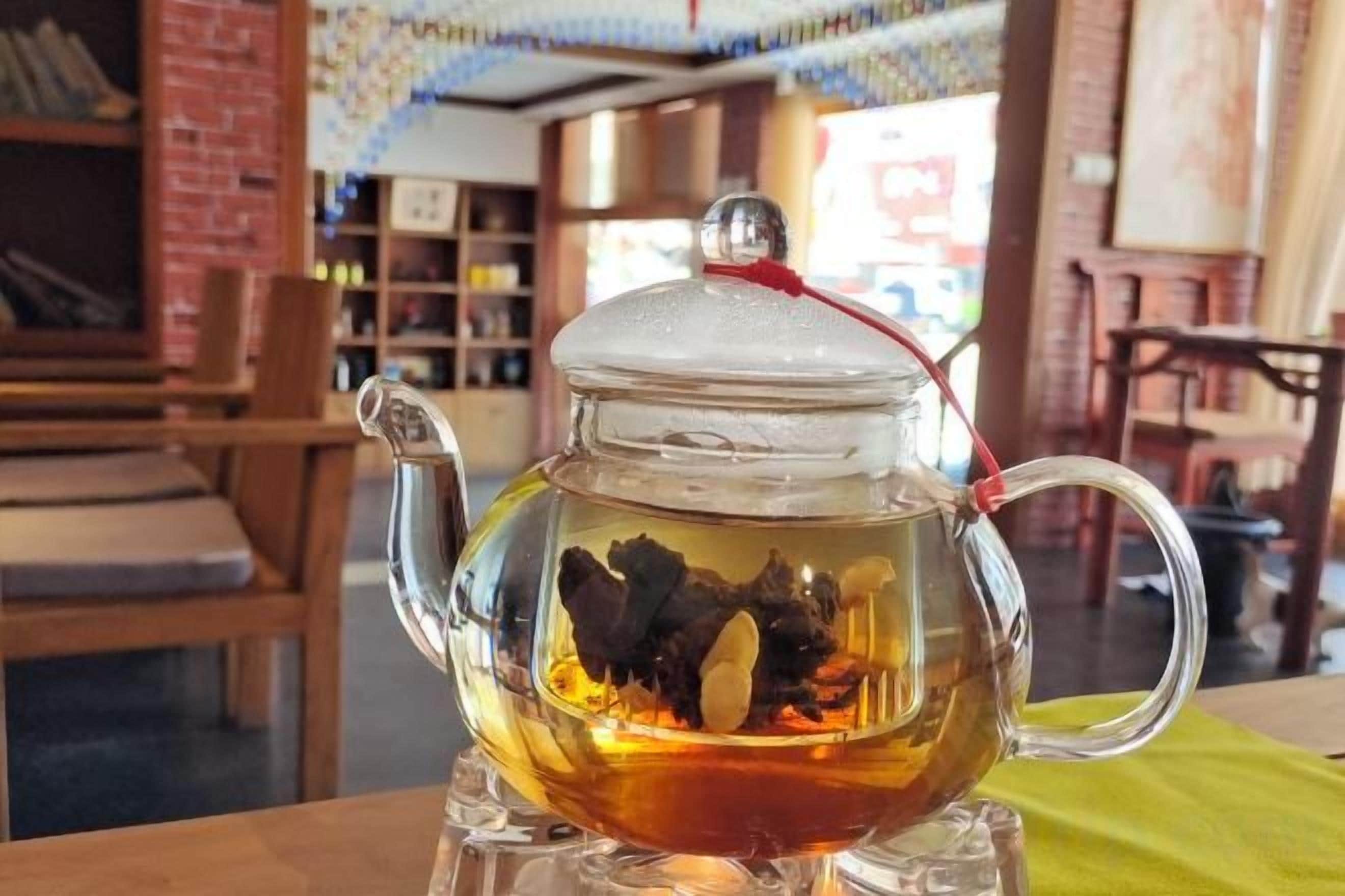 A clear glass teapot with a lid on a table.