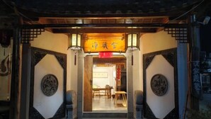 Eingang eines traditionellen chinesischen Gebäudes mit einer Holztür und einem Schild darüber.