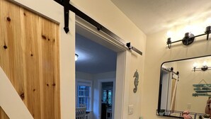 Un baño con encimera de granito, un espejo y una puerta que da a un pasillo.