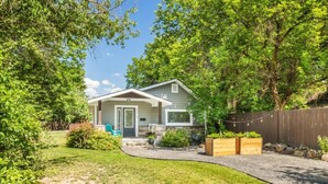 Einbungalow mit einer Veranda, einer kleinen Terrasse und einem eingezäunten Garten.