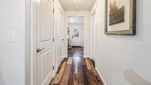 Ein Flur mit weißen Türen, Holzboden und einem gerahmten Schild an der Wand.