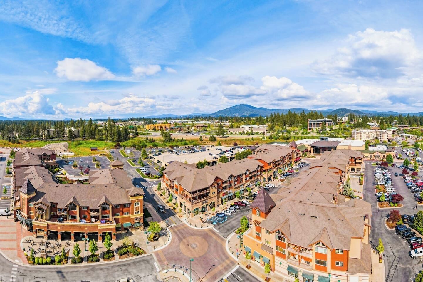 A multi-story hotel with a central courtyard, parking lot, and mountain views in the background.