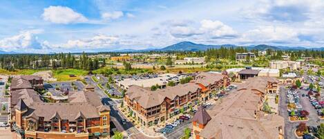 A multi-story hotel with a central courtyard, parking lot, and mountain views in the background.