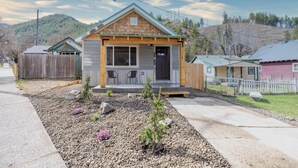 A small, single-story wooden house with a front porch, a garage, and a fenced yard. - The Silver Mountain Chalet- Private Hot Tub! (Kellogg)