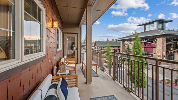 Un balcon avec des bancs en bois et une vue sur un cinéma et d’autres bâtiments.