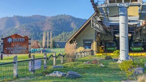 A ski resort sign, a ski lift, and a building with a ski lift. - The Silver Valley Slope - Resort and Hot Tub (Kellogg)