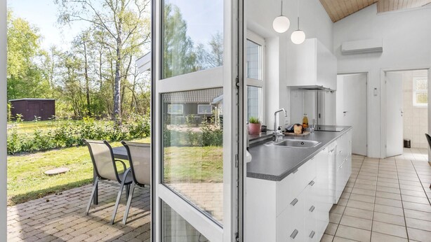 Eine moderne Küche mit großem Fenster, weißen Schränken und einer eingebauten Spüle.
