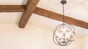 Et spiseområde med et træbord, stole, en hængende lampe og et stort vindue med udsigt.