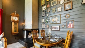 A dining room with a round wooden table, chairs, a wall-mounted clock, and framed pictures. - Broomsticks, Harry Potter themed BNB, Hot Tub! (Coeur d'Alene)