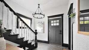 A staircase with white balusters and black handrails, a gray door with a window, and a hexagonal tile floor. - The Flat on 5th-walk to dt! (Coeur d'Alene)