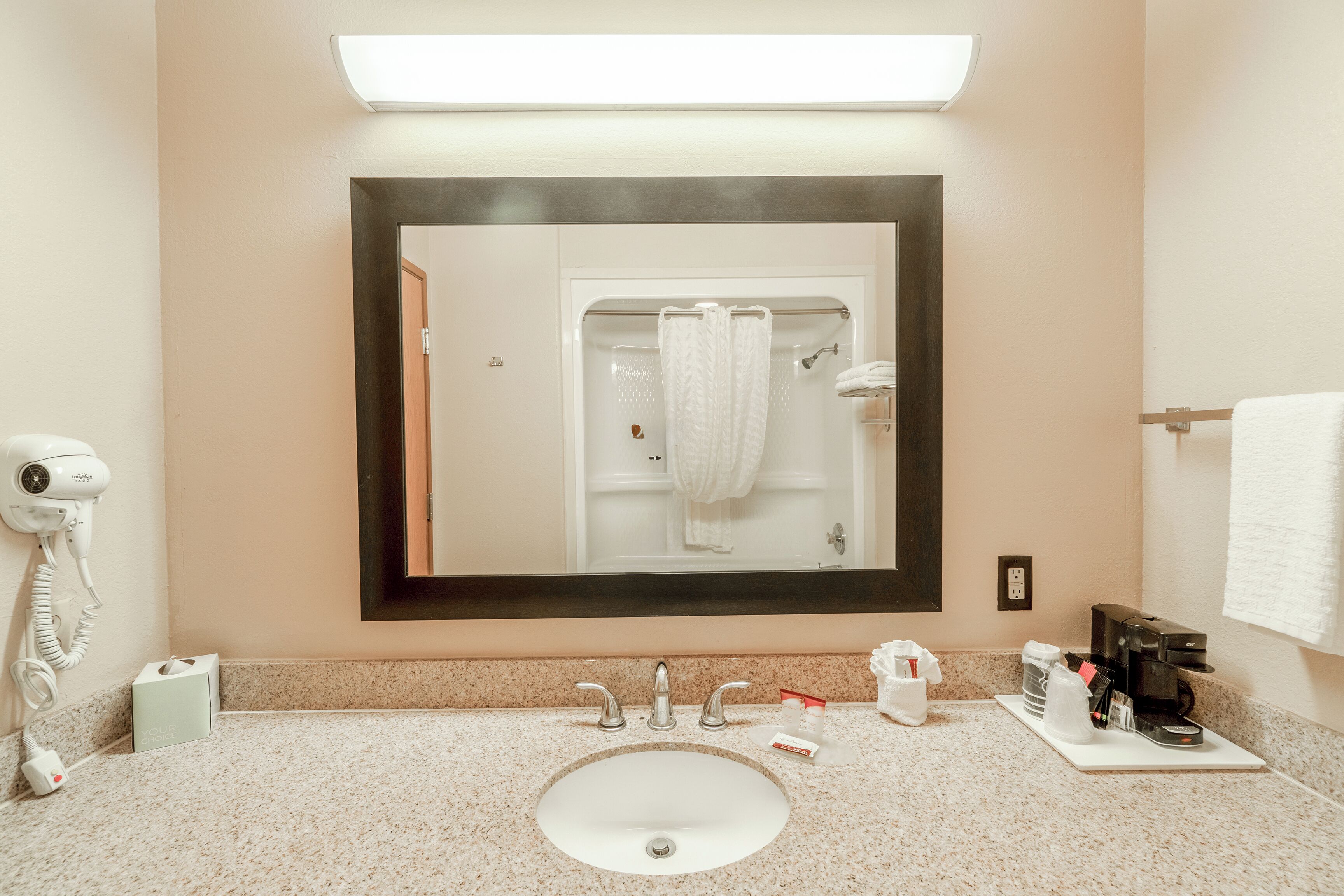 A bathroom with a sink, mirror, towel rack, and a hairdryer.