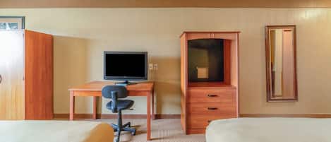 Habitación de hotel con dos camas, un escritorio con computadora, televisor, armario y espejo.