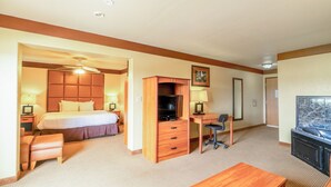 A hotel room with a bed, desk, chair, TV, and a hot tub. - Days Inn & Suites by Wyndham Beeville (Beeville)