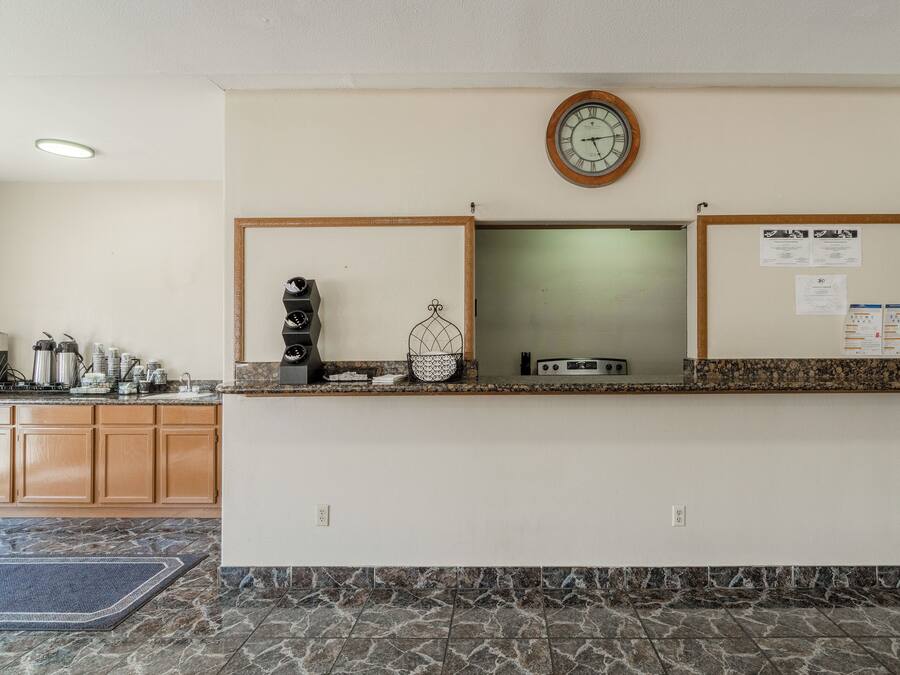 A reception area with a clock, bulletin board, and kitchen counter with appliances.